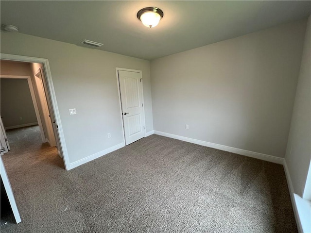 unfurnished bedroom featuring dark carpet, visible vents, and baseboards