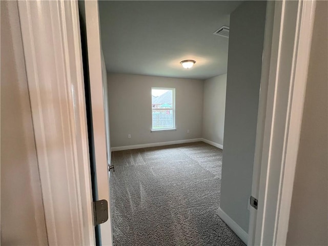 carpeted spare room with visible vents and baseboards