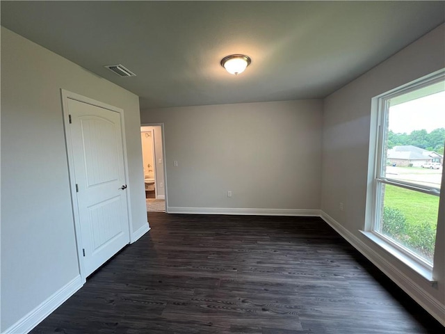 spare room featuring a wealth of natural light and dark hardwood / wood-style floors