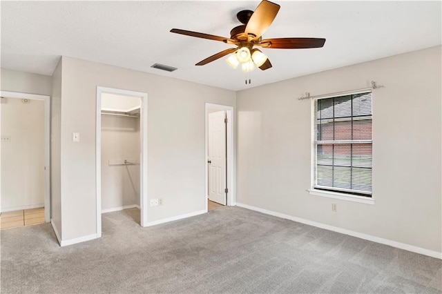 unfurnished bedroom with visible vents, baseboards, a closet, carpet, and a walk in closet