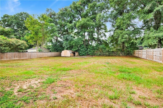 view of yard with a fenced backyard, a shed, and an outbuilding