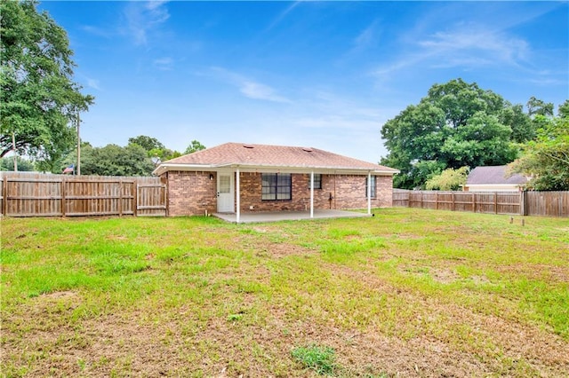 rear view of property with a yard, brick siding, a patio area, and a fenced backyard