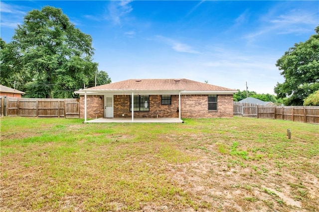 back of house featuring a patio area, a fenced backyard, a yard, and brick siding