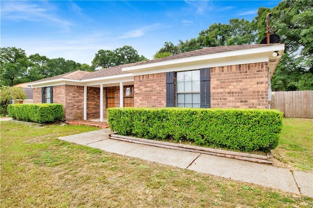 ranch-style home featuring fence, a front lawn, and brick siding