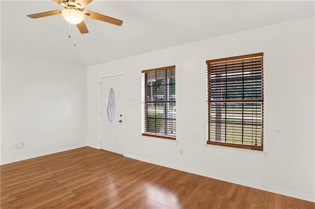 unfurnished room featuring lofted ceiling, a ceiling fan, baseboards, and wood finished floors