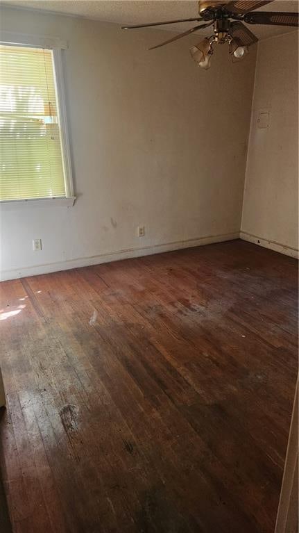 unfurnished room with dark wood-type flooring and ceiling fan