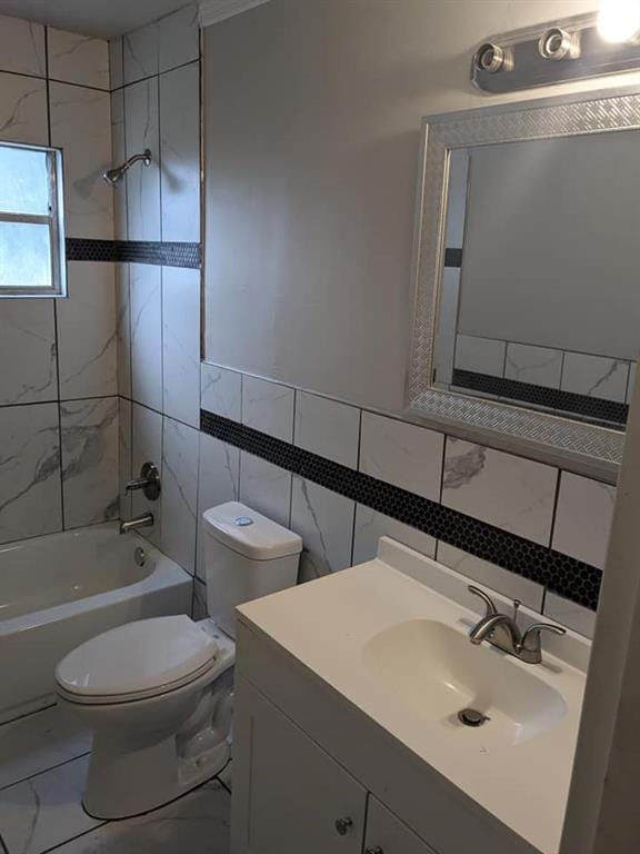 full bathroom featuring toilet, vanity, tile walls, and tiled shower / bath combo