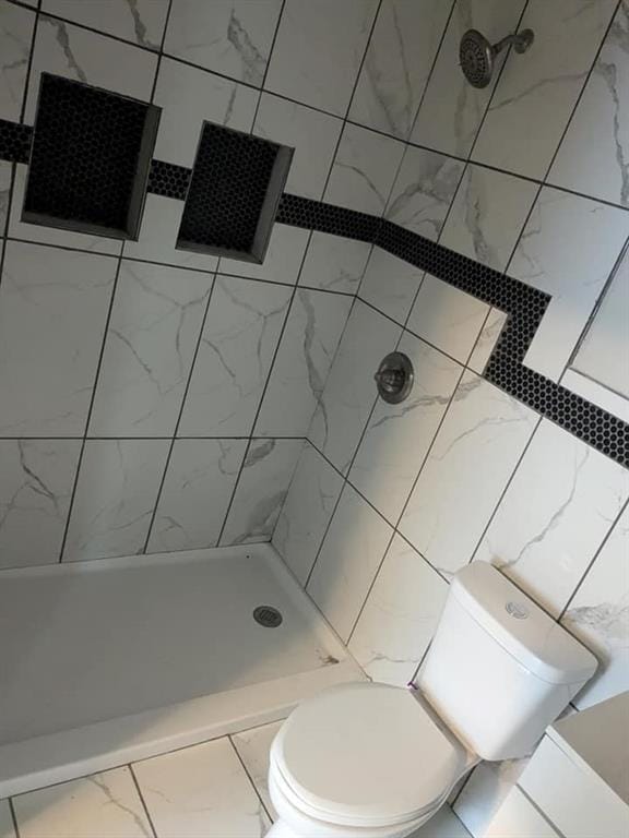 bathroom featuring a tile shower and toilet