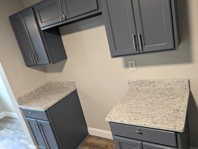 kitchen with gray cabinets, light stone counters, and dark hardwood / wood-style floors