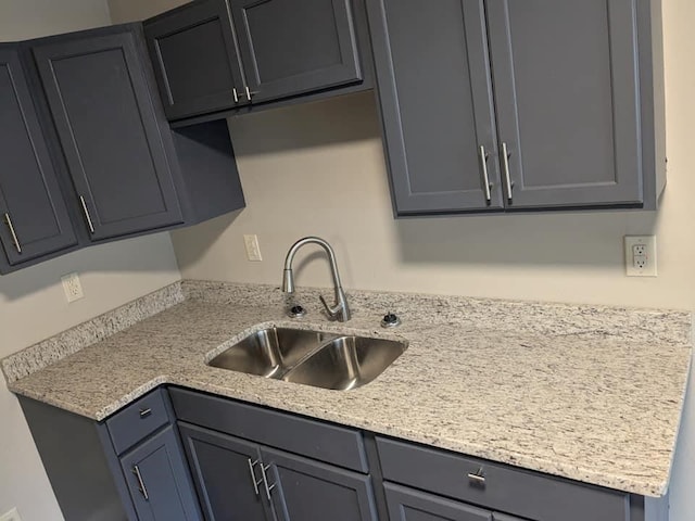 kitchen with sink, light stone counters, and gray cabinets