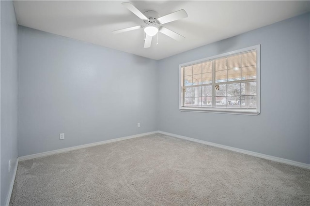 carpeted spare room with ceiling fan and baseboards