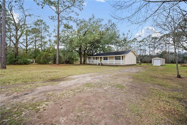 view of front of house with an outbuilding, a porch, driveway, a storage unit, and a front yard