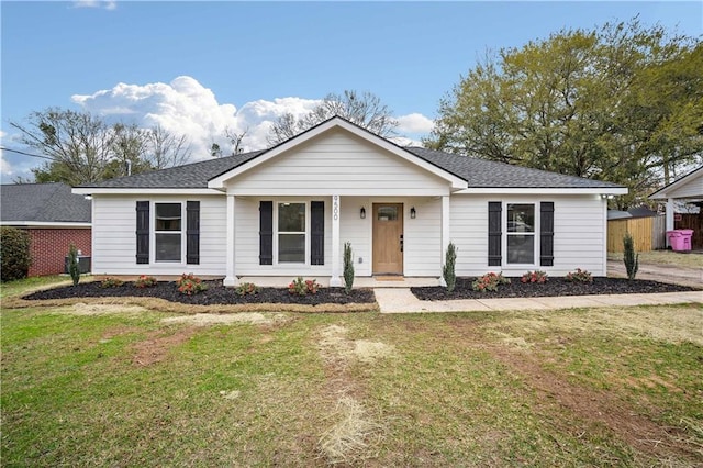 ranch-style house with covered porch, a shingled roof, a front lawn, and fence