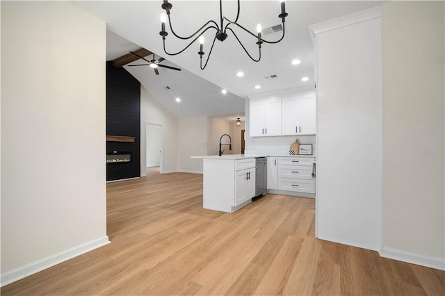 kitchen featuring a peninsula, light wood-style flooring, a sink, white cabinetry, and open floor plan