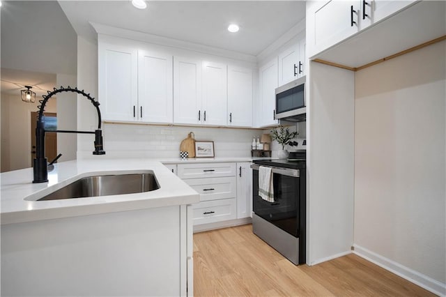 kitchen featuring a sink, stainless steel appliances, light countertops, white cabinets, and light wood-type flooring