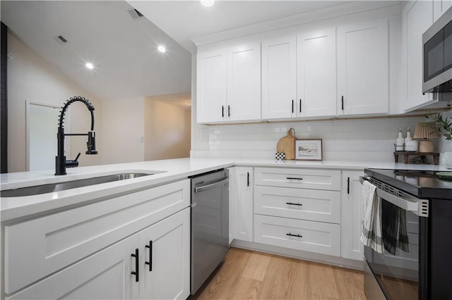 kitchen with light countertops, light wood-style flooring, appliances with stainless steel finishes, white cabinetry, and a sink