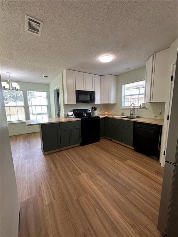 1010 Hamilton Bridges Dr E, Mobile, AL 36695 - kitchen with black appliances, light wood-type flooring, white cabinets, a sink, and a chandelier