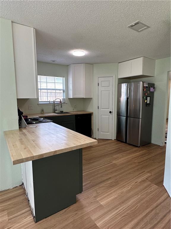 1010 Hamilton Bridges Dr E, Mobile, AL 36695 - kitchen featuring freestanding refrigerator, butcher block countertops, a sink, a peninsula, and white cabinets