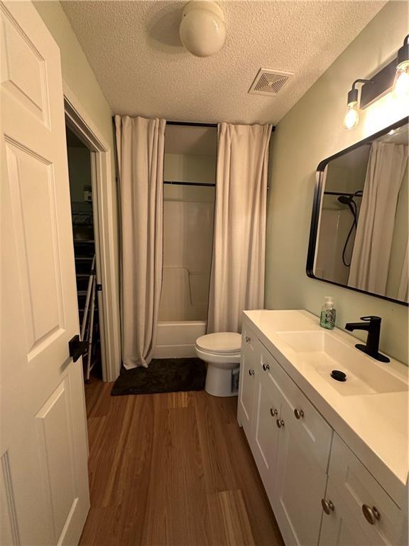 1010 Hamilton Bridges Dr E, Mobile, AL 36695 - full bath featuring a textured ceiling, wood finished floors, toilet, vanity, and shower / bath combination with curtain