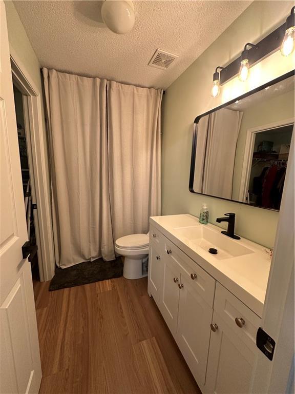 1010 Hamilton Bridges Dr E, Mobile, AL 36695 - bathroom featuring wood finished floors, a textured ceiling, toilet, and vanity
