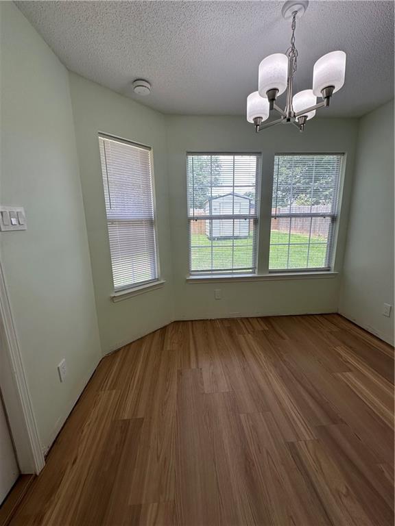 1010 Hamilton Bridges Dr E, Mobile, AL 36695 - empty room with a chandelier, wood finished floors, a textured ceiling, and a smoke detector