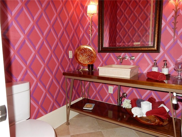 bathroom featuring toilet, tile flooring, and sink