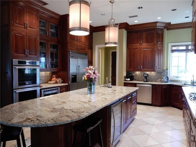 kitchen with built in appliances, pendant lighting, a kitchen island, backsplash, and beverage cooler