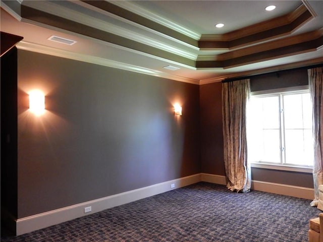 empty room featuring crown molding, dark carpet, and a tray ceiling