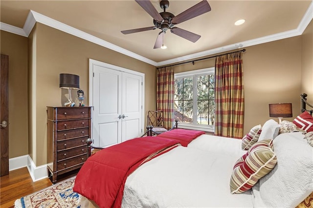 bedroom with dark hardwood / wood-style flooring, ceiling fan, ornamental molding, and a closet