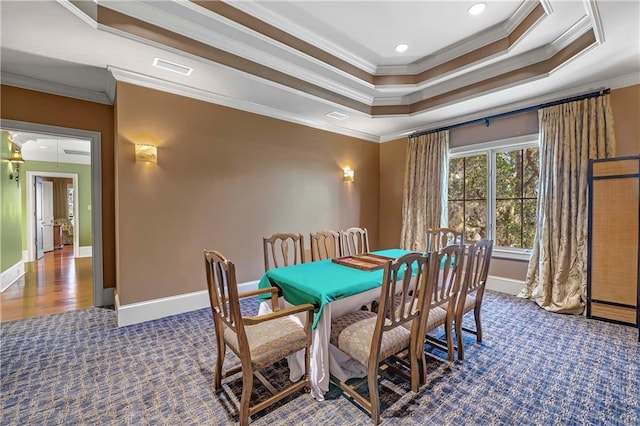 carpeted dining room with ornamental molding and a tray ceiling