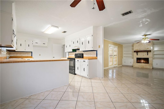 kitchen with white cabinetry, tasteful backsplash, black electric range oven, kitchen peninsula, and a fireplace