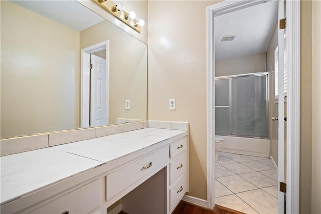 full bathroom with tile patterned flooring, vanity, toilet, and shower / bath combination with glass door