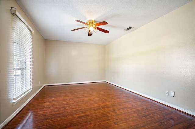 unfurnished room with a textured ceiling, ceiling fan, and dark wood-type flooring