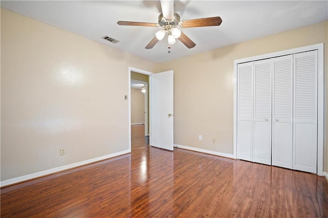 unfurnished bedroom with ceiling fan, a closet, and hardwood / wood-style flooring