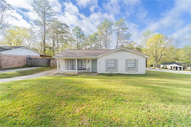 ranch-style home featuring driveway, covered porch, a front lawn, and fence
