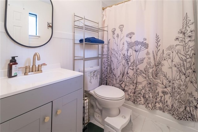 full bathroom featuring a wainscoted wall, curtained shower, toilet, and vanity