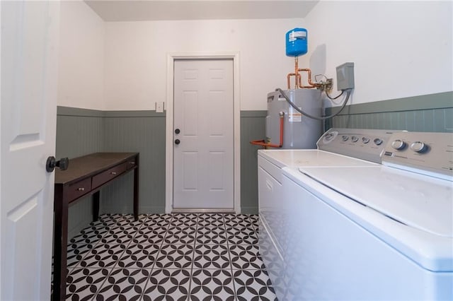 laundry room with washing machine and clothes dryer, water heater, laundry area, wainscoting, and tile patterned floors