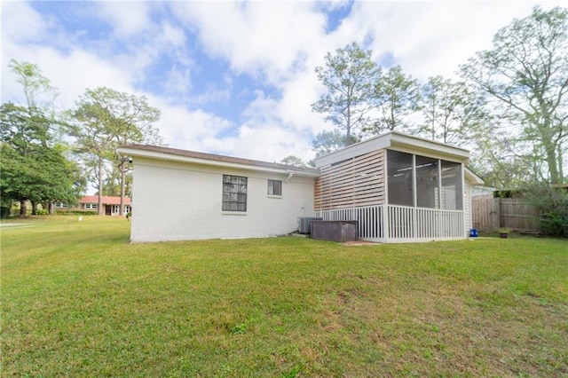 rear view of property with a yard, fence, central AC, and a sunroom