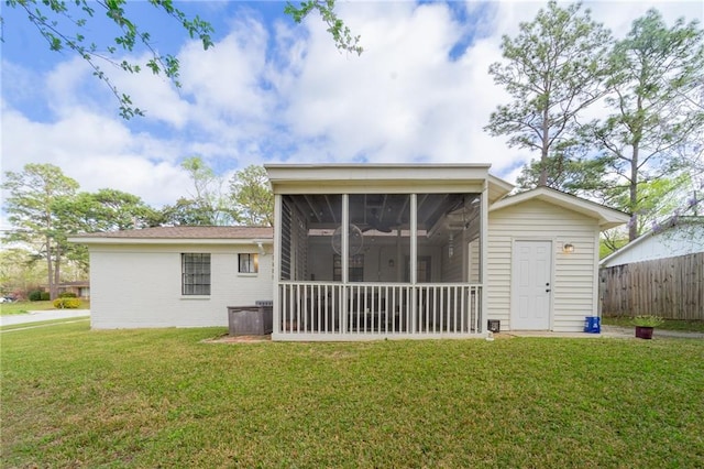 back of house featuring a yard, fence, and a sunroom