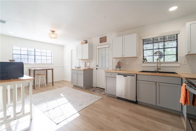 kitchen with dishwasher, gray cabinetry, light wood finished floors, and a sink