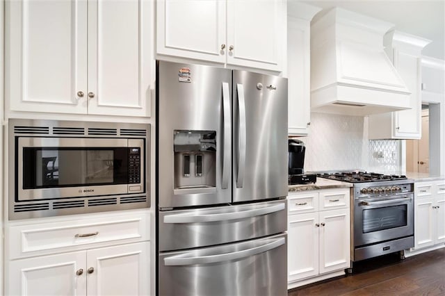 kitchen featuring premium range hood, white cabinets, light stone countertops, appliances with stainless steel finishes, and dark hardwood / wood-style flooring