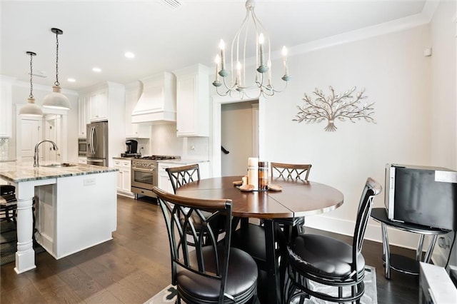 dining room with dark hardwood / wood-style flooring, an inviting chandelier, crown molding, and sink