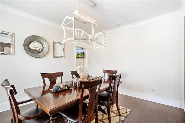 dining room featuring crown molding, dark hardwood / wood-style flooring, and an inviting chandelier