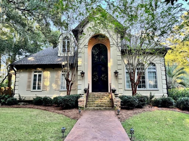 view of front of house featuring roof with shingles and a front yard