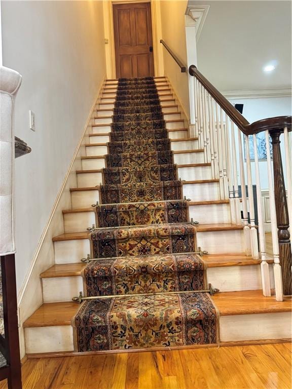 stairway featuring wood-type flooring and crown molding