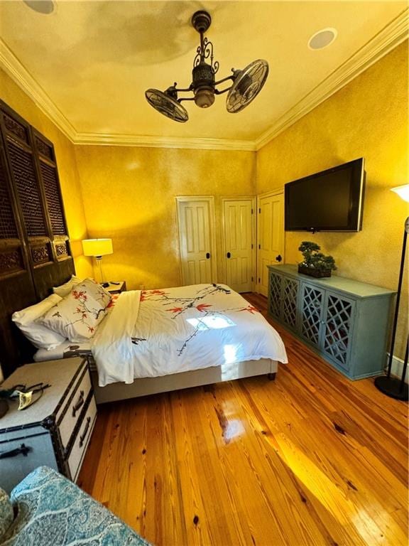 bedroom with wood-type flooring, ceiling fan, and crown molding