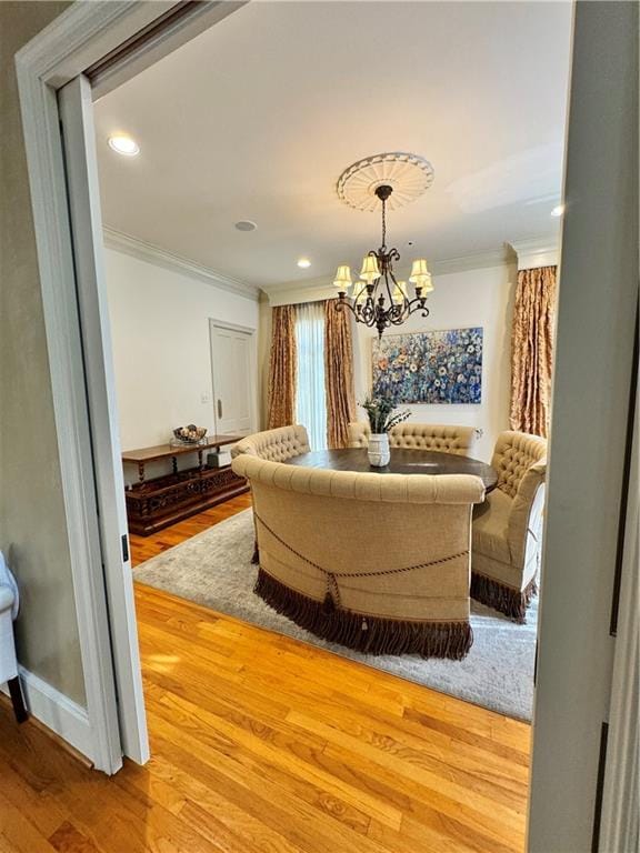 living room featuring light hardwood / wood-style floors, an inviting chandelier, and ornamental molding