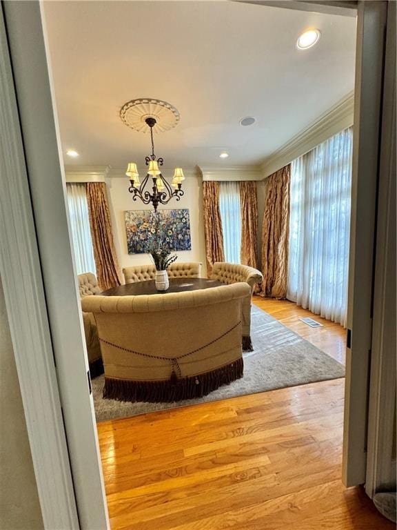 bedroom featuring light wood-type flooring, multiple windows, crown molding, and a notable chandelier