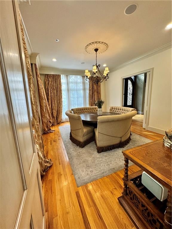 dining room with light wood-type flooring, ornamental molding, and a chandelier