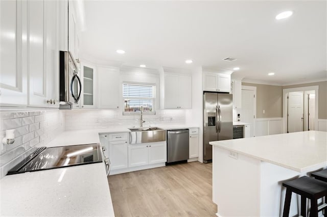 kitchen featuring white cabinets, light wood-type flooring, stainless steel appliances, and sink